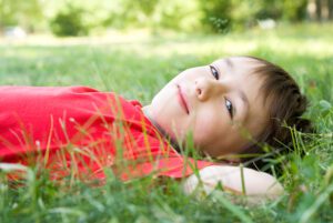 Image of calm boy lying on grass, to accompany blog: Kids' Emotional Dysregulation: What To Do, What NOT To Do
